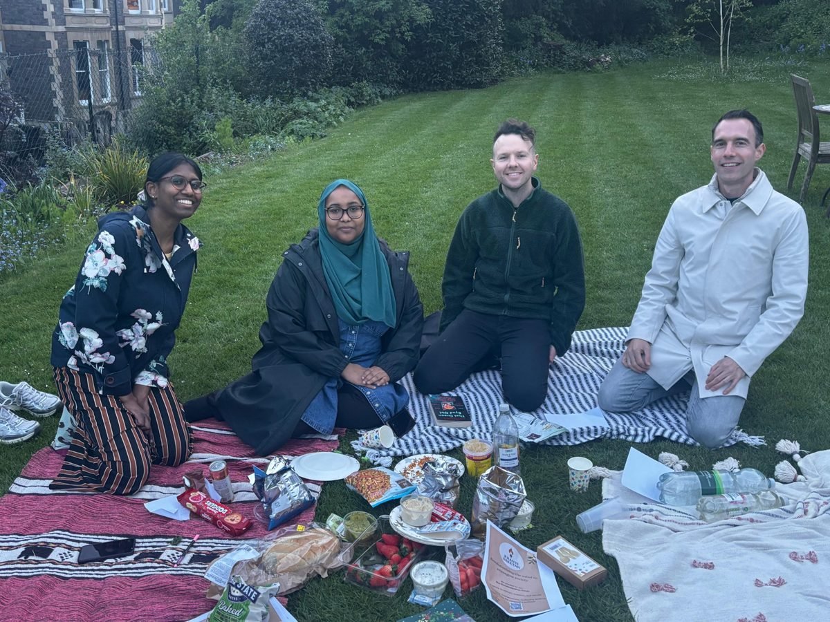 Four members of the Decolonisation Circle sitting on picnic blankets on a lawn in Bristol