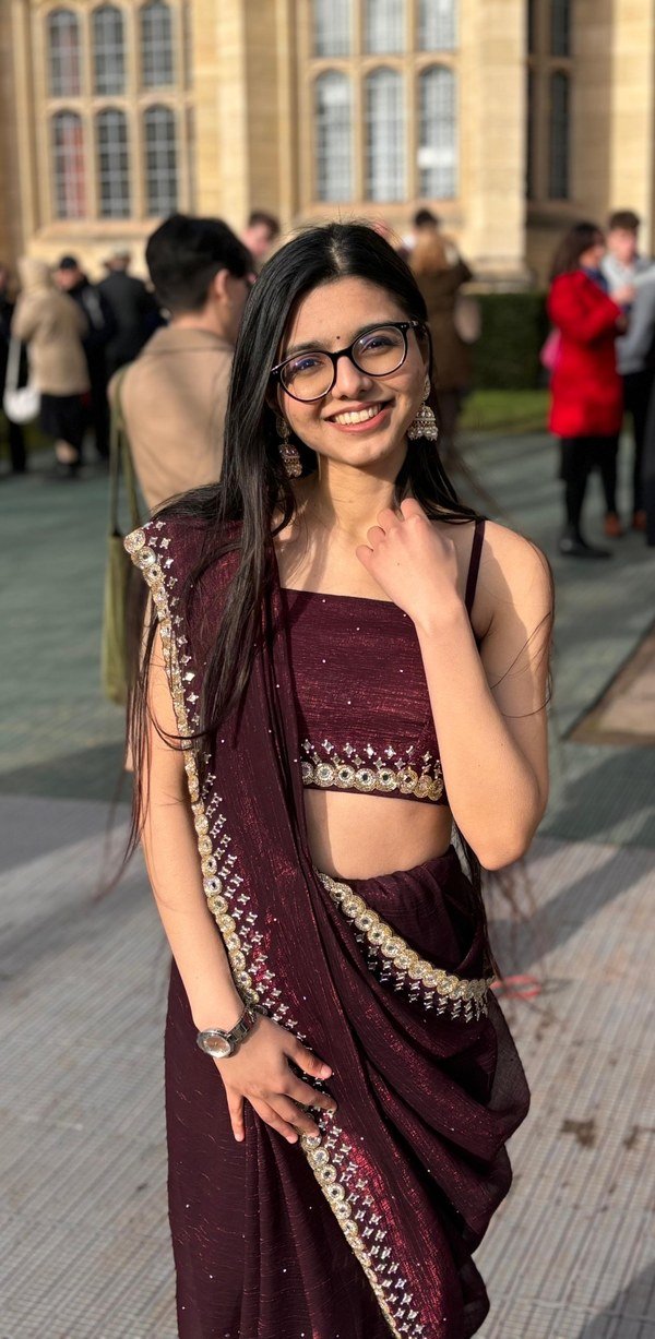 Naitri Derasari, founder of Kranti Niketan, smiling in a maroon saree and glasses
